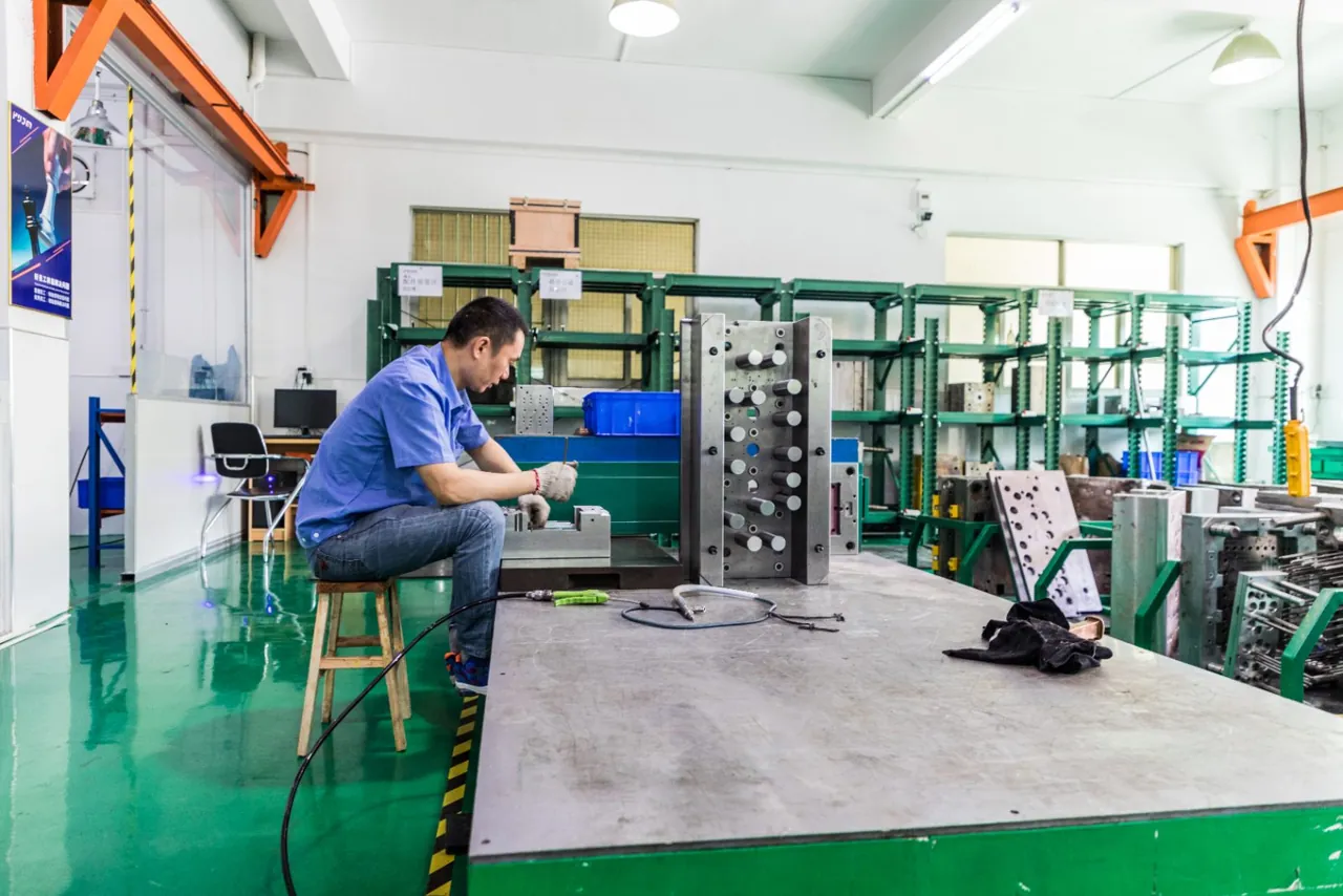 Toolmaker fitting mold components at a workbench